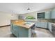 Bright kitchen with custom cabinets, a cooktop island, and a large arched window to bring the outdoors in at 1705 Nottingham Rd, Raleigh, NC 27607