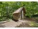Backyard view of a rustic wood shed with a red tiled roof, nestled among the trees at 1705 Nottingham Rd, Raleigh, NC 27607