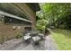 An outdoor patio with an umbrella table and four chairs surrounded by green grass and brick on the home at 1705 Nottingham Rd, Raleigh, NC 27607