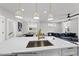 Kitchen island boasts a stainless sink, elegant pendant lights, and seamlessly connects to the inviting dining and living spaces at 219 Woodsborough Pl, Raleigh, NC 27601