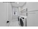 Well-lit laundry room with modern washer and dryer, storage cabinets, and a convenient hanging rack at 219 Woodsborough Pl, Raleigh, NC 27601