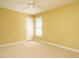 Bright bedroom features neutral carpet, yellow walls, and a ceiling fan at 230 Paula Dr, Angier, NC 27501