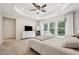 Bright Main Bedroom featuring tray ceiling, ceiling fan, dresser with TV, mirror, and large windows with backyard views at 241 White Oak Ridge Dr, Garner, NC 27529