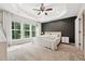 Spacious main bedroom with a tray ceiling, ceiling fan, and large windows providing natural light and lush backyard views at 241 White Oak Ridge Dr, Garner, NC 27529