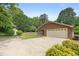 A brick detached two-car garage with ample parking space and a side storage shed surrounded by lush greenery at 2523 Lovette Ln, Graham, NC 27253