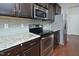 Close-up of a modern kitchen with stainless steel appliances, granite countertops, and dark wood cabinets at 321 Westgrove Ct, Durham, NC 27703