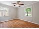 Bright bedroom features hardwood floors, ceiling fan, and two sunny windows at 3216 Idlewood Village Dr, Raleigh, NC 27610