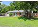 Beautiful ranch-style home with vibrant lawn, mature trees, teal front door, and charming landscaping at 3216 Idlewood Village Dr, Raleigh, NC 27610