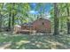 The brick home's backyard features a wooden deck with stairs and mature trees at 3221 Ward Rd, Raleigh, NC 27604