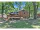 Backyard of brick home featuring a wooden deck with stairs, a little grass, and mature trees at 3221 Ward Rd, Raleigh, NC 27604