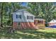 Two-story home with a brick foundation and light siding, set in a lush yard with mature shade trees at 3221 Ward Rd, Raleigh, NC 27604
