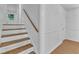 Clean stairway featuring wooden steps and railing, connecting different levels of the home at 3221 Ward Rd, Raleigh, NC 27604