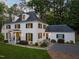 Elegant white two-story home with black shutters, manicured lawn, and dark roof against a backdrop of mature trees at 3540 Rugby Rd, Durham, NC 27707