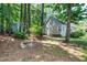 View of a charming home nestled in a wooded setting, featuring a cozy backyard fire pit and lush greenery at 3616 Culater Ct, Raleigh, NC 27616
