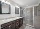 Bathroom with dual sink granite vanity, framed mirrors, and a glass-enclosed tile shower at 3901 Yates Mill Trl, Raleigh, NC 27606
