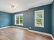 This is a bedroom with hardwood floors, teal walls, white molding and trim, and two windows at 3901 Yates Mill Trl, Raleigh, NC 27606