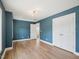 Bright bedroom featuring wood-look floors, blue walls, a closet, and an open door to the landing at 3901 Yates Mill Trl, Raleigh, NC 27606