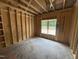 Bedroom framed with unfinished walls and a view of the backyard through a large window at 4024 N Nc 581 Hwy, Kenly, NC 27542