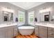 Modern bathroom featuring dual vanities, hardwood floors, natural lighting, and a standalone tub at 405 Culvert St, Apex, NC 27502