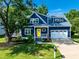 Charming two-story blue home with a bright yellow front door, manicured lawn, and attached two-car garage at 405 Culvert St, Apex, NC 27502