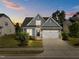 Beautiful twilight view of home with a stone and gray shake facade, complemented by a well-manicured lawn and a two-car garage at 427 Cedar Pond Ct, Knightdale, NC 27545