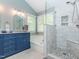Bright bathroom showcasing a blue vanity, tub, and tiled shower with decorative mosaic accents at 5536 Centipede Trl, Raleigh, NC 27610
