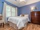 Bright blue bedroom with laminate floor, large window, light bedding and a wood dresser at 5536 Centipede Trl, Raleigh, NC 27610