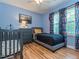 Blue bedroom featuring a grey daybed and dresser, next to a baby crib with playful bedding at 5536 Centipede Trl, Raleigh, NC 27610