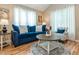Bright living room featuring a blue sofa, round coffee table, and white curtains at 5536 Centipede Trl, Raleigh, NC 27610