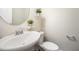 A sleek powder room with a pedestal sink, round mirror, and decorative plants on floating shelves at 6107 Kayton St, Raleigh, NC 27616