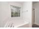 Bright bathroom featuring a white tub beneath a window, with glass shower doors at 642 Pinevalley Ln, Sanford, NC 27332