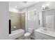 Well-lit bathroom features a shower-tub combo, tile surround, window, and modern fixtures at 7117 Crested Iris Pl, Durham, NC 27703