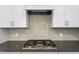 Gas range detail with herringbone backsplash and white cabinetry in modern kitchen at 7117 Crested Iris Pl, Durham, NC 27703