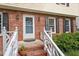 Close-up of the front door, white railings, and a brick facade creating an inviting entry at 7209 St Ledger Dr, Raleigh, NC 27613