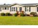 Attractive single-story home with a black door, wooden steps, landscaping, and vinyl siding at 764 Olivers Grove Rd, Four Oaks, NC 27524