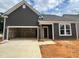 New construction home showcasing a two-car garage and stylish gray siding under a cloudy sky at 798 Old Station Pointe, Angier, NC 27501