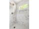Bright bathroom shower with marble tiling, pebble floor, gold fixtures, and natural light at 939 Clarion Dr, Durham, NC 27705