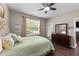 Sunlit bedroom with hardwood floors, a ceiling fan, a dresser, and a door to the outside at 100 Tobacco Leaf Ln, Apex, NC 27502