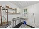 Functional laundry room with sink, metal table, white cabinetry, and a water heater, perfect for household tasks at 1022 Dorothea Dr, Raleigh, NC 27603
