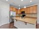 Kitchen with wood cabinets, granite countertops, stainless steel refrigerator, and a central island with a sink at 103 Ransomwood Dr, Apex, NC 27539