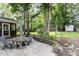 Private backyard with mature trees, stone border, patio set, and storage shed at 105 Acorn Ridge Ln, Holly Springs, NC 27540