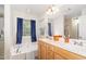 Bathroom offers a soaking tub with a window, double sink vanity, large mirror and a shower with glass doors at 105 Acorn Ridge Ln, Holly Springs, NC 27540