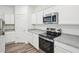 Well-lit kitchen with stainless steel range and microwave, white cabinets, and granite countertops at 1212 Solace Way, Rolesville, NC 27571