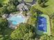 Stunning aerial view of a community pool, tennis court, and clubhouse surrounded by lush landscaping and mature trees at 1317 Woodgate Manor Ct, Raleigh, NC 27614