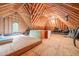 View of a spacious attic with exposed wooden beams, plywood flooring, and a window offering natural light at 1317 Woodgate Manor Ct, Raleigh, NC 27614