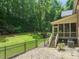 A screen porch leads to a fenced yard with mature trees and lush green grass at 1317 Woodgate Manor Ct, Raleigh, NC 27614