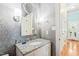 Stylish bathroom featuring granite vanity, modern lighting, decorative mirror, and patterned wallpaper at 1317 Woodgate Manor Ct, Raleigh, NC 27614