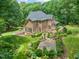 View of a brick home in a landscaped yard with patio, fire pit and mature trees at 1317 Woodgate Manor Ct, Raleigh, NC 27614