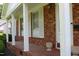 Inviting covered front porch with brick columns and a tiled floor, perfect for relaxing outdoors at 2071 Meadow Ln, Graham, NC 27253