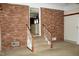 Stairs feature brick wall and leads into adjacent room; features neutral carpet and painted wood railings at 2071 Meadow Ln, Graham, NC 27253